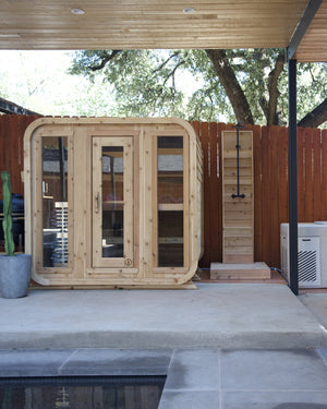 Cedar cabin sauna with three glass panels, an outdoor shower and a cold plunge on a covered poolside patio
